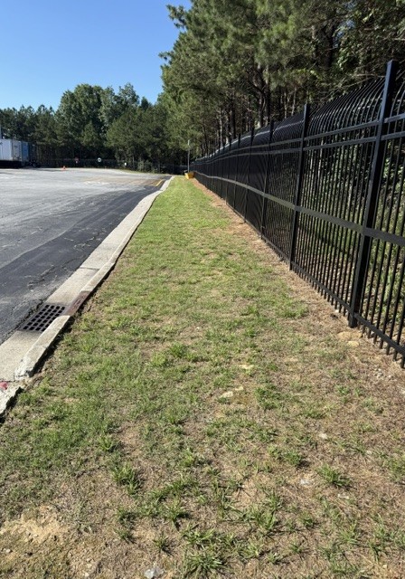 Black metal fence line bordering commercial parking lot