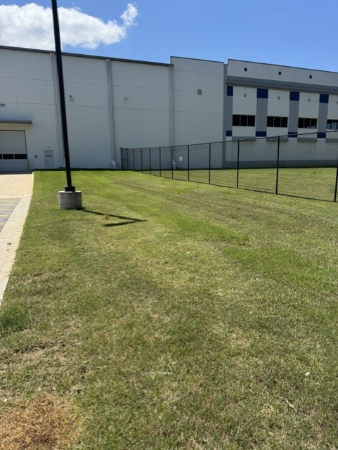 Maintained grass and chain-link fence along warehouse perimeter